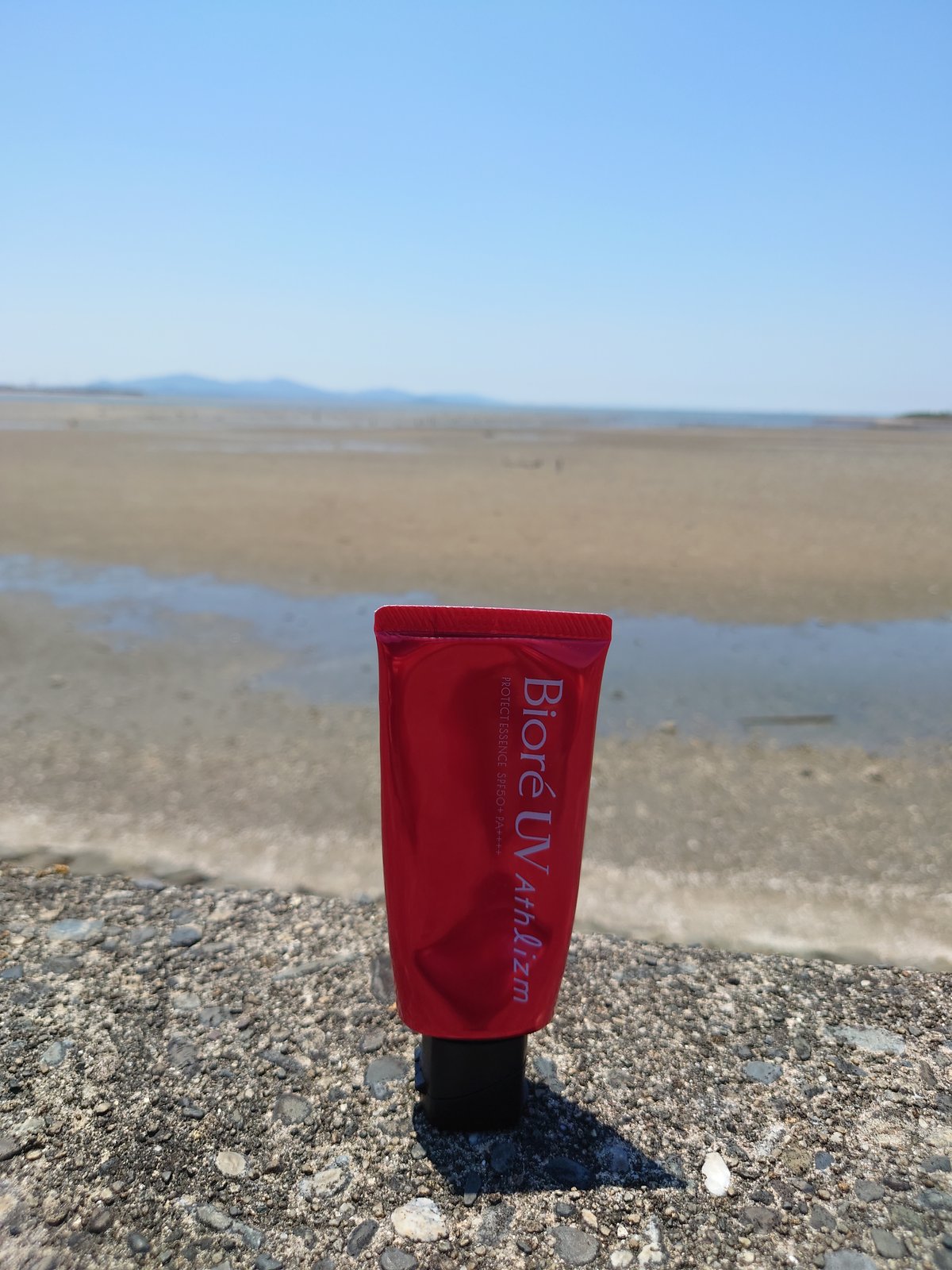 海岸の堤防に置かれたビオレ UV アスリズム SPF50+ PA++++